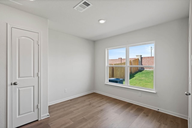 empty room featuring wood finished floors, visible vents, and baseboards