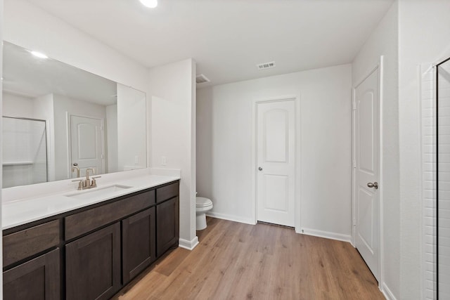 bathroom with baseboards, visible vents, toilet, wood finished floors, and vanity