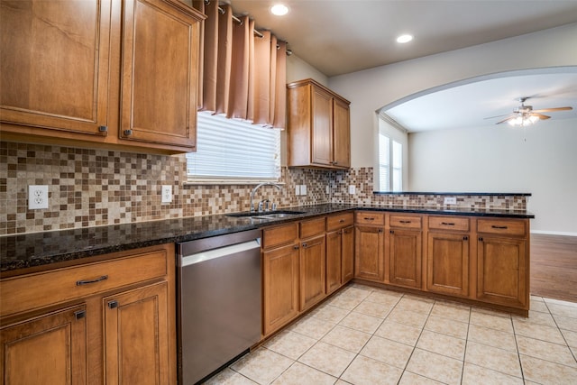 kitchen with tasteful backsplash, brown cabinetry, light tile patterned flooring, a sink, and dishwasher