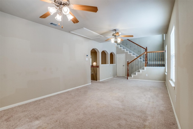 carpeted spare room with attic access, visible vents, baseboards, ceiling fan, and stairway