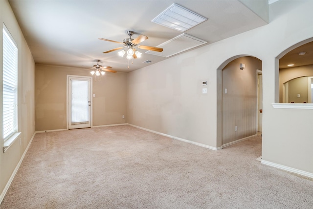 spare room featuring arched walkways, visible vents, carpet flooring, ceiling fan, and baseboards