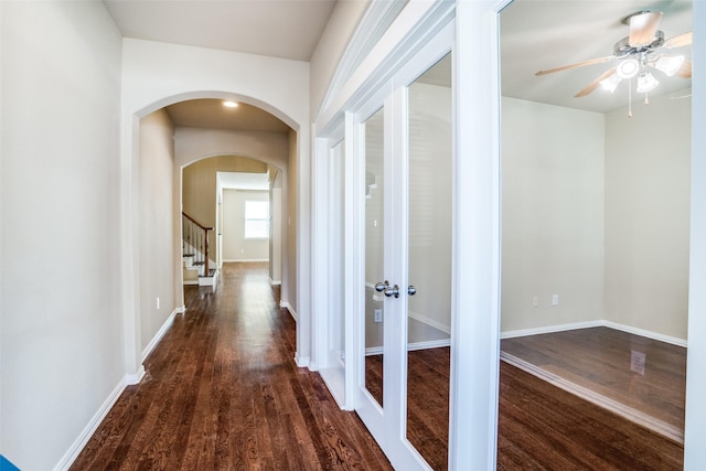 hallway with baseboards, arched walkways, dark wood-style flooring, and french doors