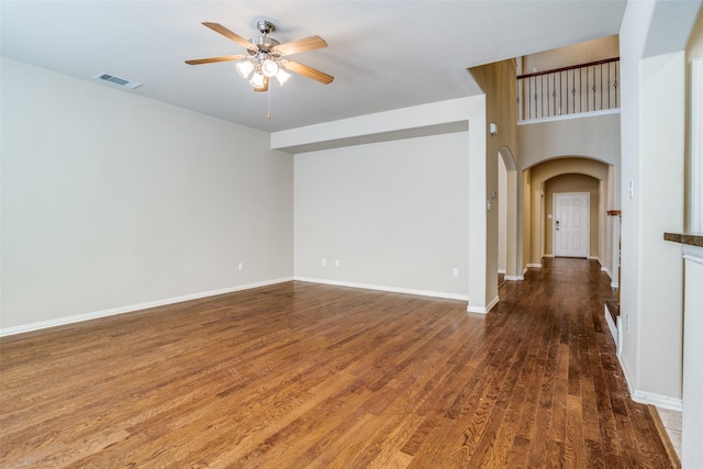 spare room with baseboards, visible vents, a ceiling fan, arched walkways, and wood finished floors