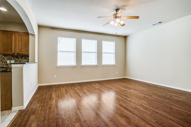 unfurnished living room featuring ceiling fan, wood finished floors, visible vents, and baseboards