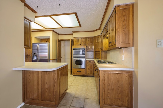 kitchen featuring brown cabinets, a peninsula, stainless steel appliances, and light countertops