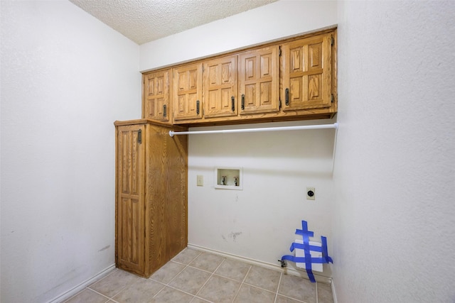 washroom with light tile patterned floors, a textured ceiling, hookup for a washing machine, hookup for an electric dryer, and cabinet space