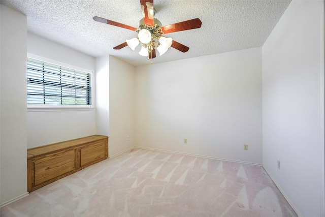 spare room with light carpet, ceiling fan, and a textured ceiling