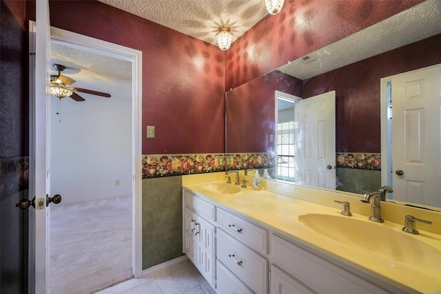 full bath featuring double vanity, a textured ceiling, a sink, and tile patterned floors