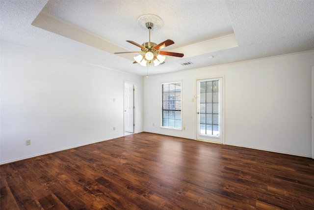 empty room featuring a textured ceiling, wood finished floors, a raised ceiling, and visible vents