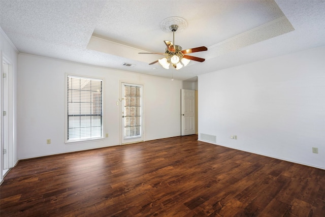 spare room with a tray ceiling, a textured ceiling, and wood finished floors