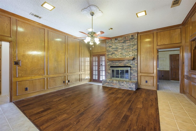 unfurnished living room with a brick fireplace, visible vents, a decorative wall, and a textured ceiling