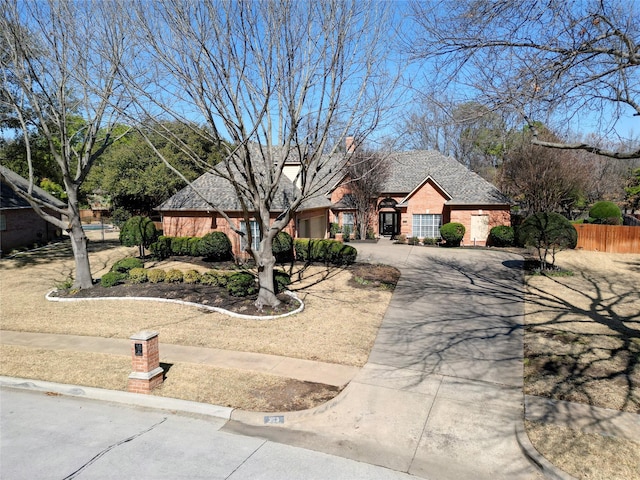 view of front of property with brick siding, driveway, and fence