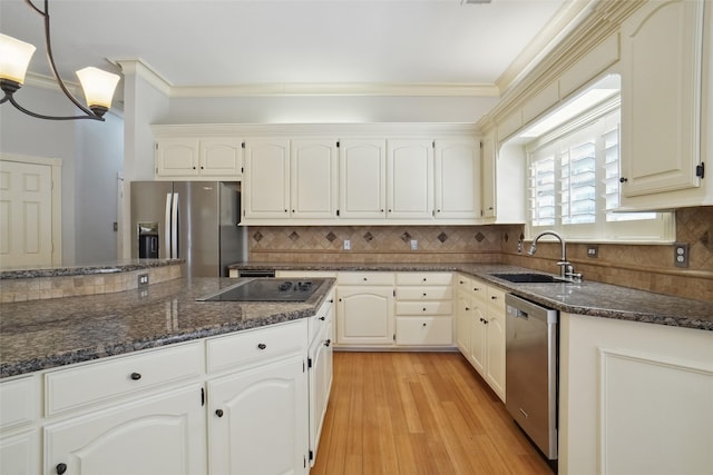 kitchen with appliances with stainless steel finishes, ornamental molding, dark stone countertops, a sink, and backsplash