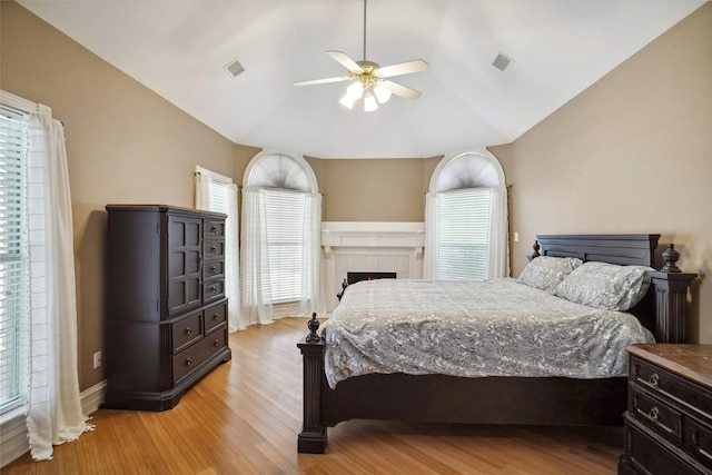 bedroom featuring lofted ceiling, light wood finished floors, visible vents, and a ceiling fan