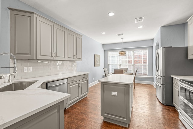 kitchen featuring gray cabinetry, stainless steel appliances, dark wood-style flooring, a sink, and visible vents