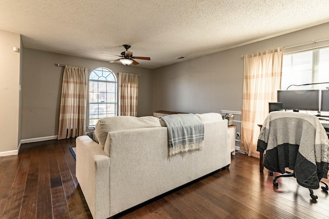 bedroom featuring a textured ceiling, ceiling fan, multiple windows, and dark wood-type flooring