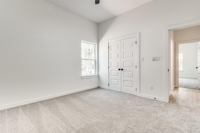 unfurnished bedroom featuring light carpet, baseboards, and a closet