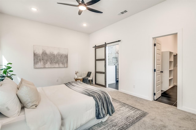 bedroom with dark colored carpet, a barn door, visible vents, and recessed lighting