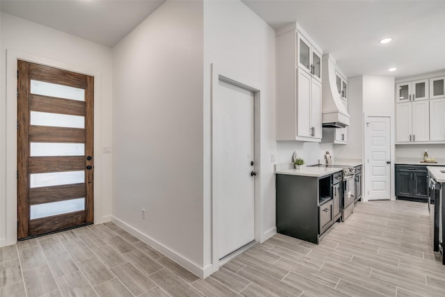 kitchen with recessed lighting, light countertops, glass insert cabinets, white cabinets, and stainless steel range with electric stovetop