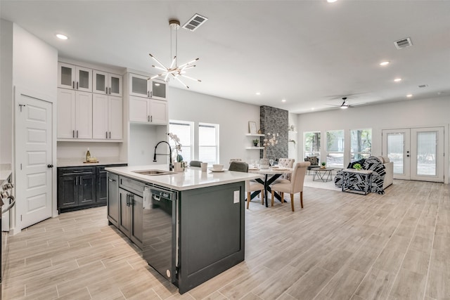 kitchen with a sink, visible vents, black dishwasher, light countertops, and open floor plan