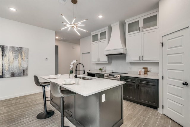 kitchen featuring electric stove, premium range hood, a sink, and wood tiled floor