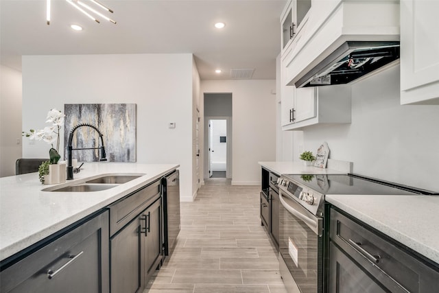 kitchen featuring light countertops, appliances with stainless steel finishes, white cabinetry, a sink, and premium range hood