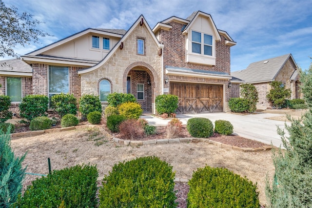 view of front of house featuring a garage, driveway, brick siding, and stone siding