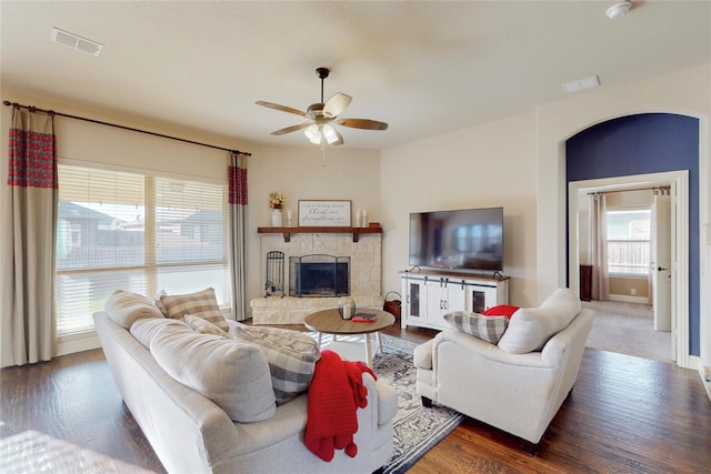 living area featuring ceiling fan, a fireplace, wood finished floors, and visible vents