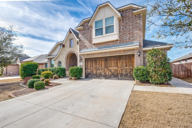 view of front of house with driveway, stone siding, fence, and brick siding