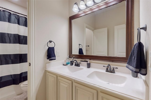 bathroom with double vanity, a shower with shower curtain, a sink, and toilet