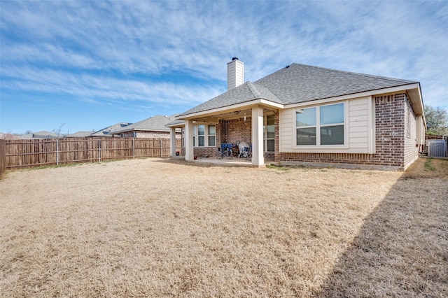 back of house featuring brick siding, a chimney, a patio area, cooling unit, and a fenced backyard