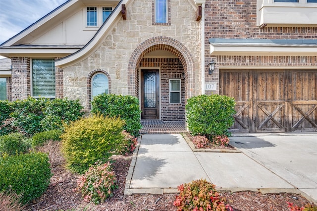 property entrance with a garage, stone siding, and brick siding