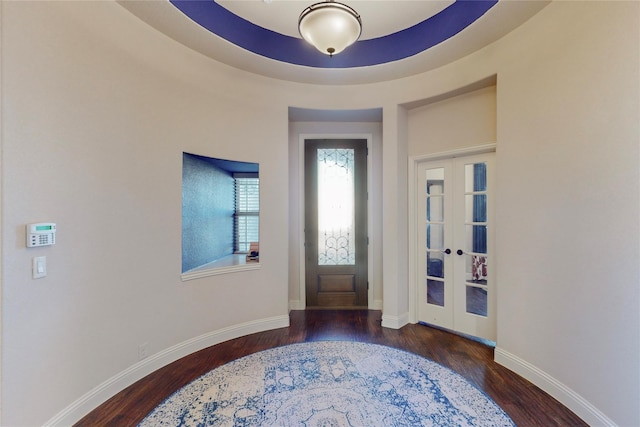 foyer entrance with a tray ceiling, french doors, wood finished floors, and baseboards