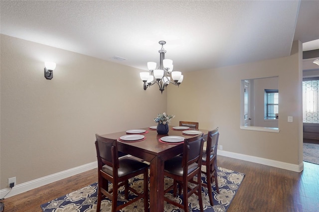 dining room featuring a notable chandelier, wood finished floors, visible vents, and baseboards