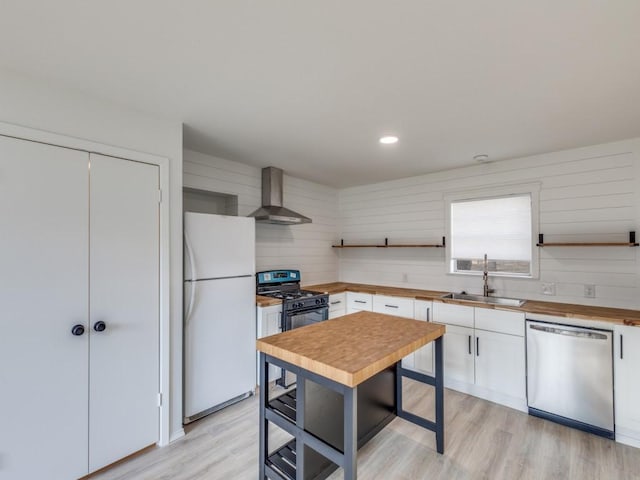 kitchen with dishwasher, wall chimney exhaust hood, freestanding refrigerator, open shelves, and a sink