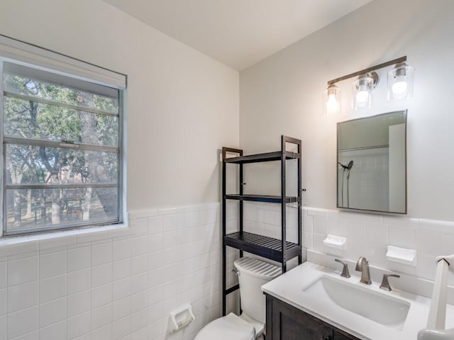 bathroom featuring toilet, a wainscoted wall, tile walls, and vanity