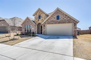 traditional-style home featuring driveway, stone siding, and a garage