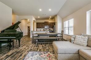 living room featuring arched walkways, wood finished floors, and recessed lighting