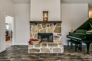 sitting room featuring a stone fireplace, wood finished floors, and baseboards