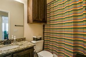 bathroom featuring curtained shower, vanity, and toilet