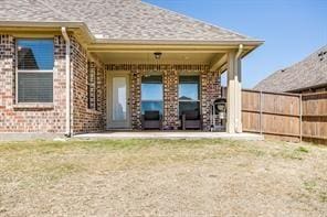 back of house with brick siding and fence