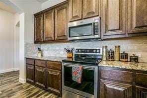 kitchen featuring stainless steel appliances, dark wood-type flooring, dark brown cabinets, and decorative backsplash