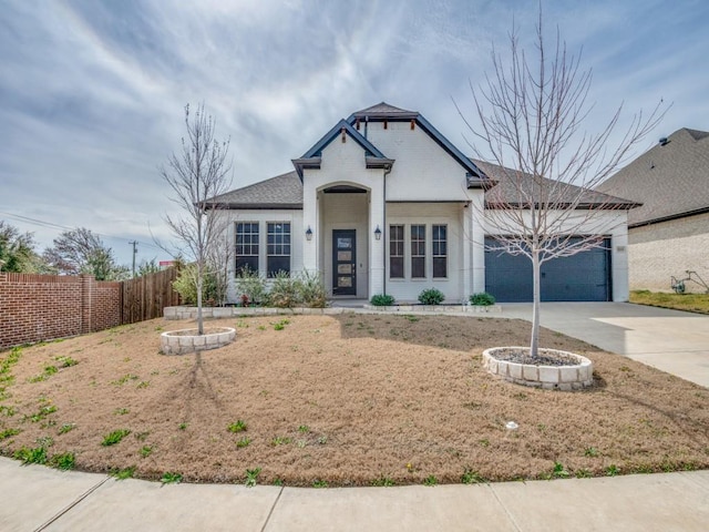 view of front of home with concrete driveway, fence, and an attached garage