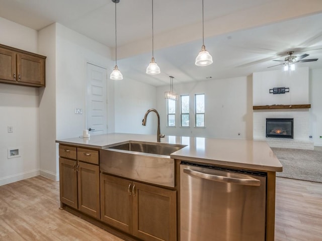 kitchen featuring dishwasher, open floor plan, light wood-style floors, pendant lighting, and a sink