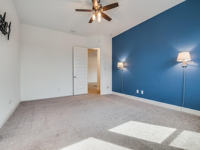 carpeted empty room featuring ceiling fan and baseboards