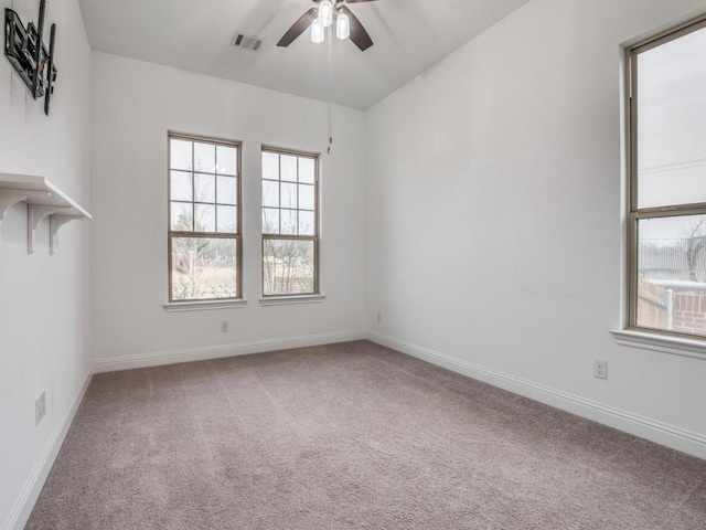 carpeted empty room with a ceiling fan, visible vents, and baseboards