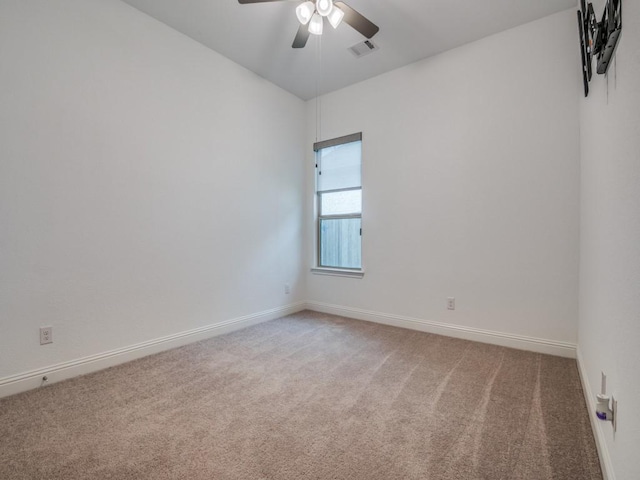 carpeted spare room featuring a ceiling fan, visible vents, and baseboards