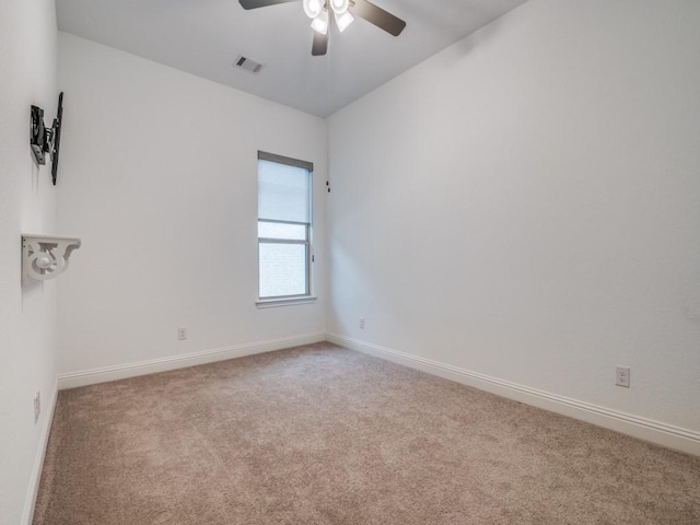 carpeted empty room featuring a ceiling fan, visible vents, and baseboards