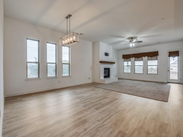 unfurnished living room with light wood finished floors, a fireplace, and a healthy amount of sunlight