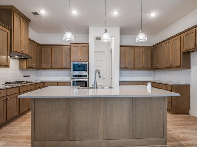 kitchen featuring appliances with stainless steel finishes, light countertops, a sink, and under cabinet range hood